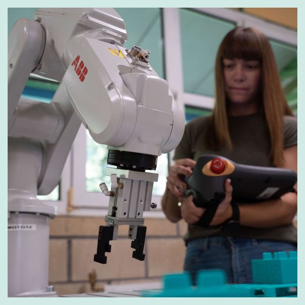 Alumnado trabajando con brazo de robot industrial ABB en curso para trabajadores